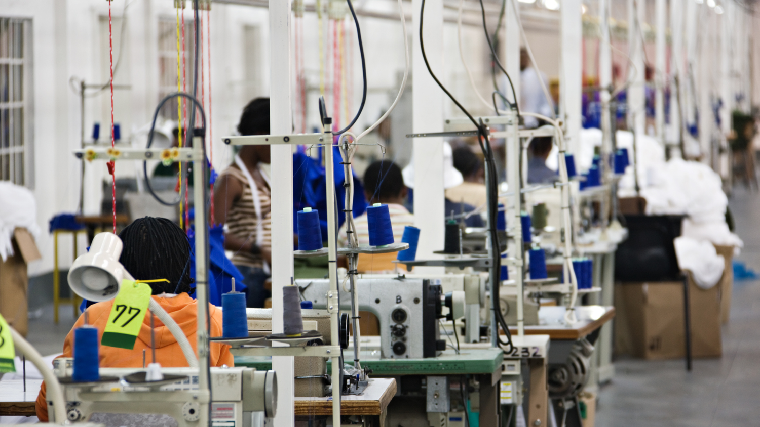Factory interior with workers operating sewing machines.