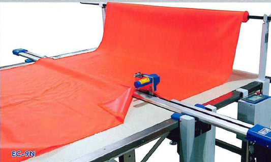 Eastman EC-9N end cutting machine on its table track, trimming a fabric spread to length